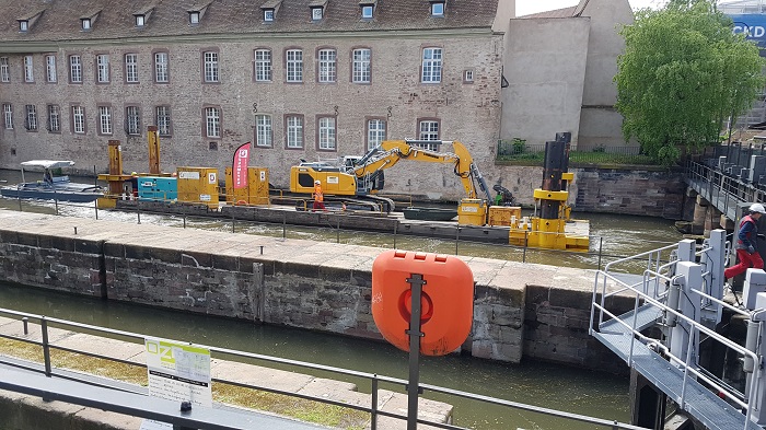 La pelle mécanique servant au battage des palplanches a dû travailler depuis un ponton installé au milieu de l'Ill. © V.N.F. Strasbourg Les travaux de la future passe à poissons de Strasbourg