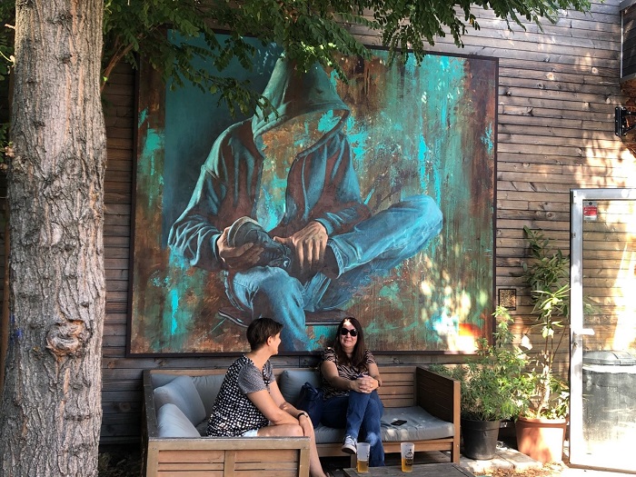 Certaines des fresques sont peintes en extérieur. Dans le jardin des Ateliers éclairés, celle de Piet Rodriguez, dont le fond évoque une plaque de cuivre. LG : Certaines des fresques sont peintes en extérieur. Dans le jardin des Ateliers éclairés, celle de Piet Rodriguez, dont le fond évoque une plaque de cuivre.