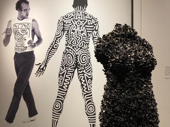 Une vidéo du chorégraphe Bill T Jones derrière une œuvre singulière, Le cheval de Troie, de Johan Creten, un buste composé de fleurs noires en céramique, telles qu’on en trouvait autrefois sur les tombes, au Mamcs. Exposition "Aux temps du sida"